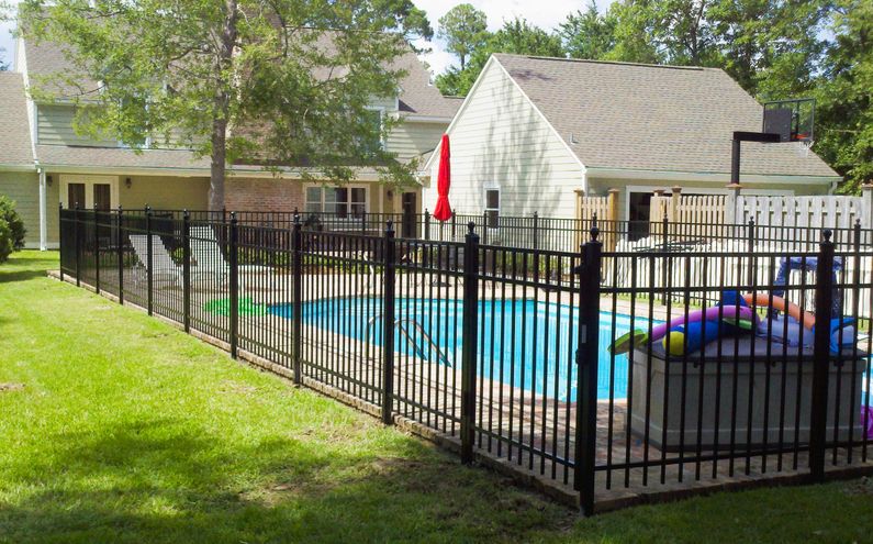 A black aluminum fence enclosing a backyard swimming pool