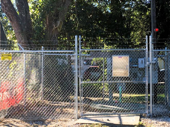 A tall galvanized chain-link fence and gate at a commercial site