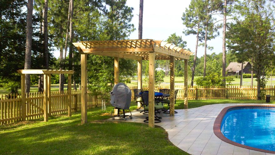 A backyard pool framed by a wood picket fence and pergola